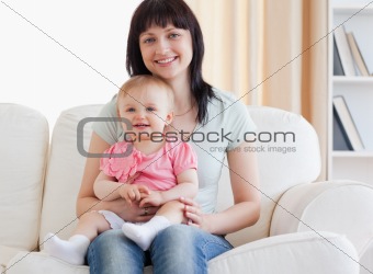 Beautiful woman holding her baby in her arms while sitting on a 