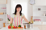 Attractive brunette woman posing while cooking vegetables