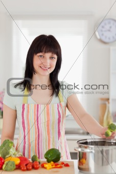 Good looking brunette woman posing while cooking vegetables