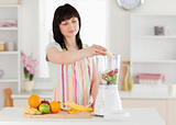 Lovely brunette woman putting vegetables in a mixer while standi