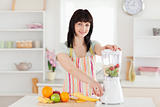 Attractive brunette woman using a mixer while standing