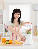 Beautiful brunette woman using a mixer while standing