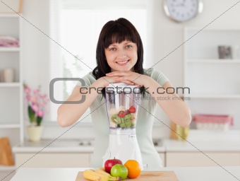 Good looking brunette woman posing with a mixer while standing