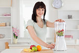 Charming brunette woman using a mixer while standing