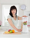 Good looking brunette female using a mixer while standing
