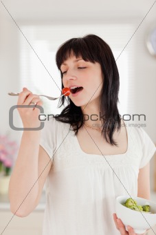 Beautiful brunette female eating a cherry tomato while holding a