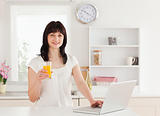 Attractive brunette woman holding a glass of orange juice while 