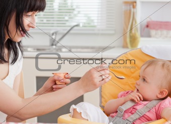 Beautiful brunette woman feeding her baby while sitting