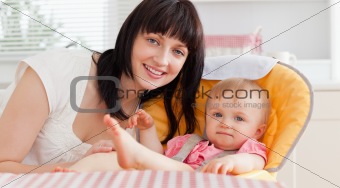 Beautiful brunette woman posing with her baby while sitting