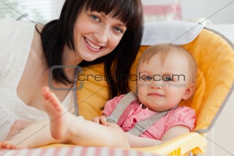 Good looking brunette woman posing with her baby while sitting