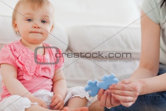 Woman showing a puzzle piece to her baby while sitting on a carp