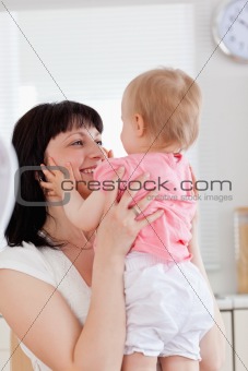 Gorgeous brunette woman holding her baby in her arms while sitti