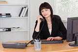 Pretty brunette woman on the phone while working on a computer