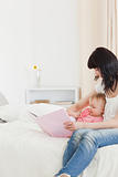 Good looking brunette woman showing a book to her baby while sit