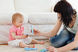 Beautiful woman and her baby playing with puzzle pieces while si