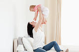 Charming brunette woman playing with her baby while sitting on a