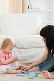 Attractive woman and her baby playing with puzzle pieces while s