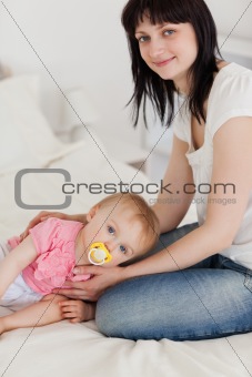 Attractive brunette female posing with her baby lying on her