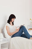 Charming brunette woman reading a book while sitting on a bed