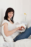 Attractive brunette woman relaxing with her laptop while sitting