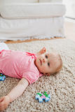 Lovely blond baby playing with puzzle pieces while lying on a ca