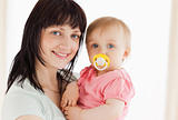 Attractive woman holding her baby in her arms while standing