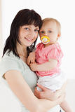 Good looking woman holding her baby in her arms while standing