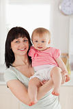 Attractive woman holding her baby in her arms while standing
