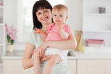 Charming woman holding her baby in her arms while standing