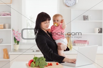Beautiful brunette woman in suit holding her baby in her arms wh