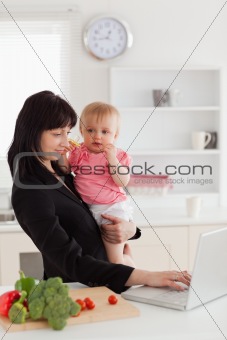 Attractive brunette woman in suit holding her baby in her arms w