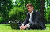 Young businessman resting in a park on the grass