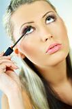 Portrait of blonde young sexy woman doing makeup