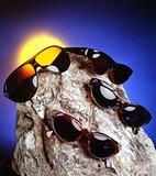 Four sunglasses over a nice stone