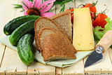 still life in a rustic style - cheese, tomatoes, cucumbers, rye bread on a wooden table