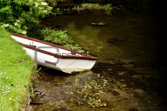 Small boat in a rural stream parked at the bank