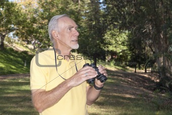 Active senior man birdwatching in wood