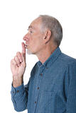 Elderly man with finger to lips for silence
