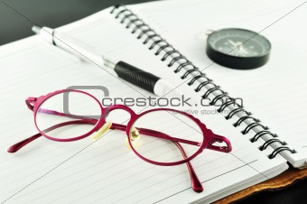 Notebook with pen and glasses 