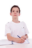 cute boy on the desk studying and thinking, isolated on white, studio shot