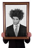man holding a decorative frame and standing inside it on black and white, isolated on white, studio shot