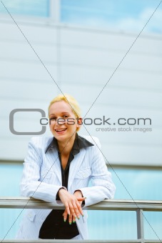Pensive business woman leaning on railing at office building 
