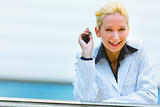 Smiling business woman with mobile in hand leaning on railing at office building
