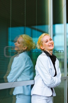 Laughing business woman with crossed arms on chest at office building 
