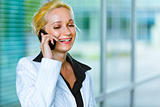 Smiling business woman talking on mobile at office building 

