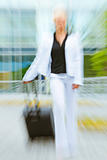 Rushing business woman with suitcase walking on street . Motion blur
