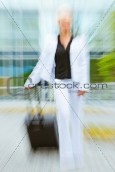 Rushing business woman with suitcase walking on street . Motion blur

