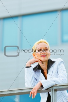 Thinking about something business woman leaning on railing at office building 
