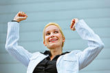 Excited  business woman standing at office building  and rejoicing her success 
