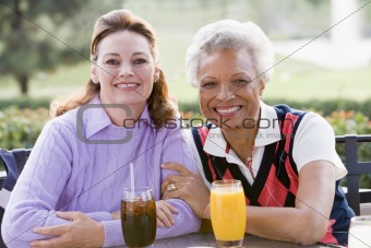 Two Female Friends Enjoying A Beverage By A Golf Course